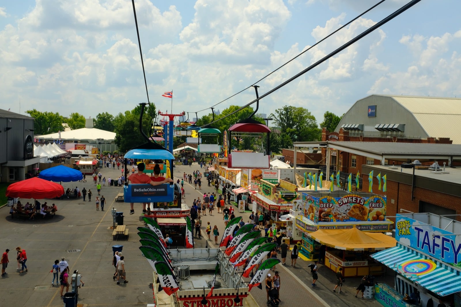 Ohio State Fair food stands advertising stromboli, deep-fried sweets, and taffy along the midway, seen from above