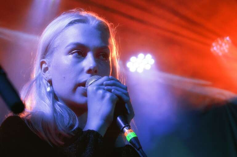 You Can Hear Phoebe Bridgers' New Album Early Inside COSI's Planetarium 4 woman singing into mircrophone