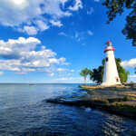 The Ultimate Ohio Coastal Road Trip: Where to Stop, Stay & Explore Marblehead Lighthouse on the rocky Lake Erie shoreline under a blue sky