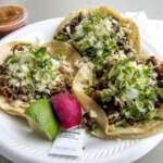 Columbus Taco Week Is Back With $10-And-Under Taco Deals Across Central Ohio Three street tacos with carnitas, carne asada and al pastor on a paper plate with lime and radish