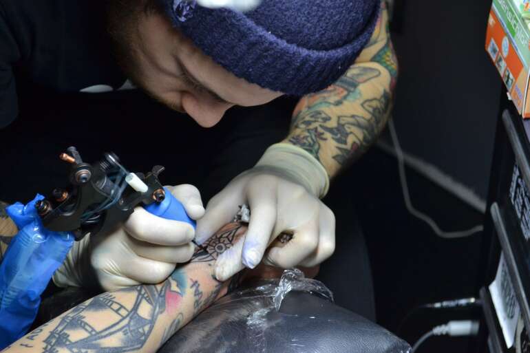 The Best Tattoo Shops In Columbus 4 A tattoo artist outlining a design on a client's arm