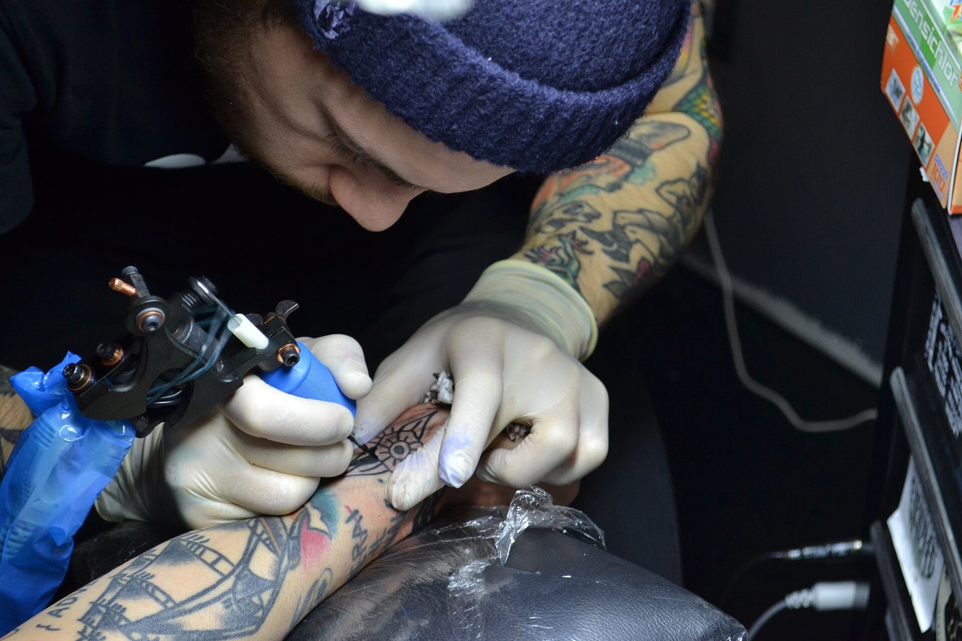 A tattoo artist outlining a design on a client's arm