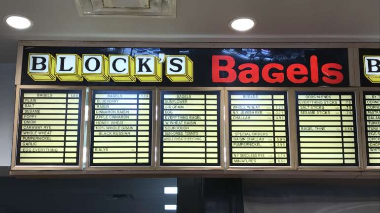 Block's Bagels sign and lit menu boards listing plain, salt, sesame and other bagel varieties