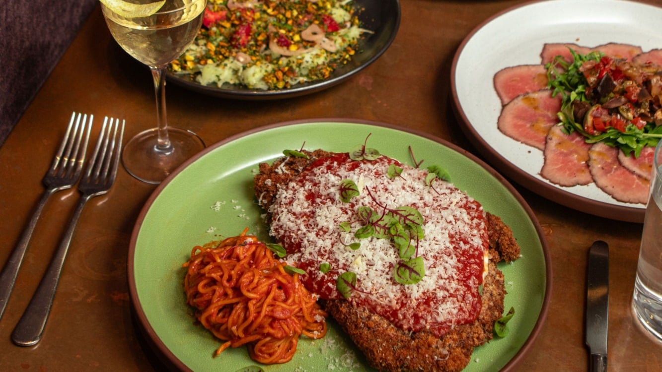 Chicken parmesan with spaghetti in red sauce beside a plate of beef carpaccio at Metsi's Wood-Fired Italian