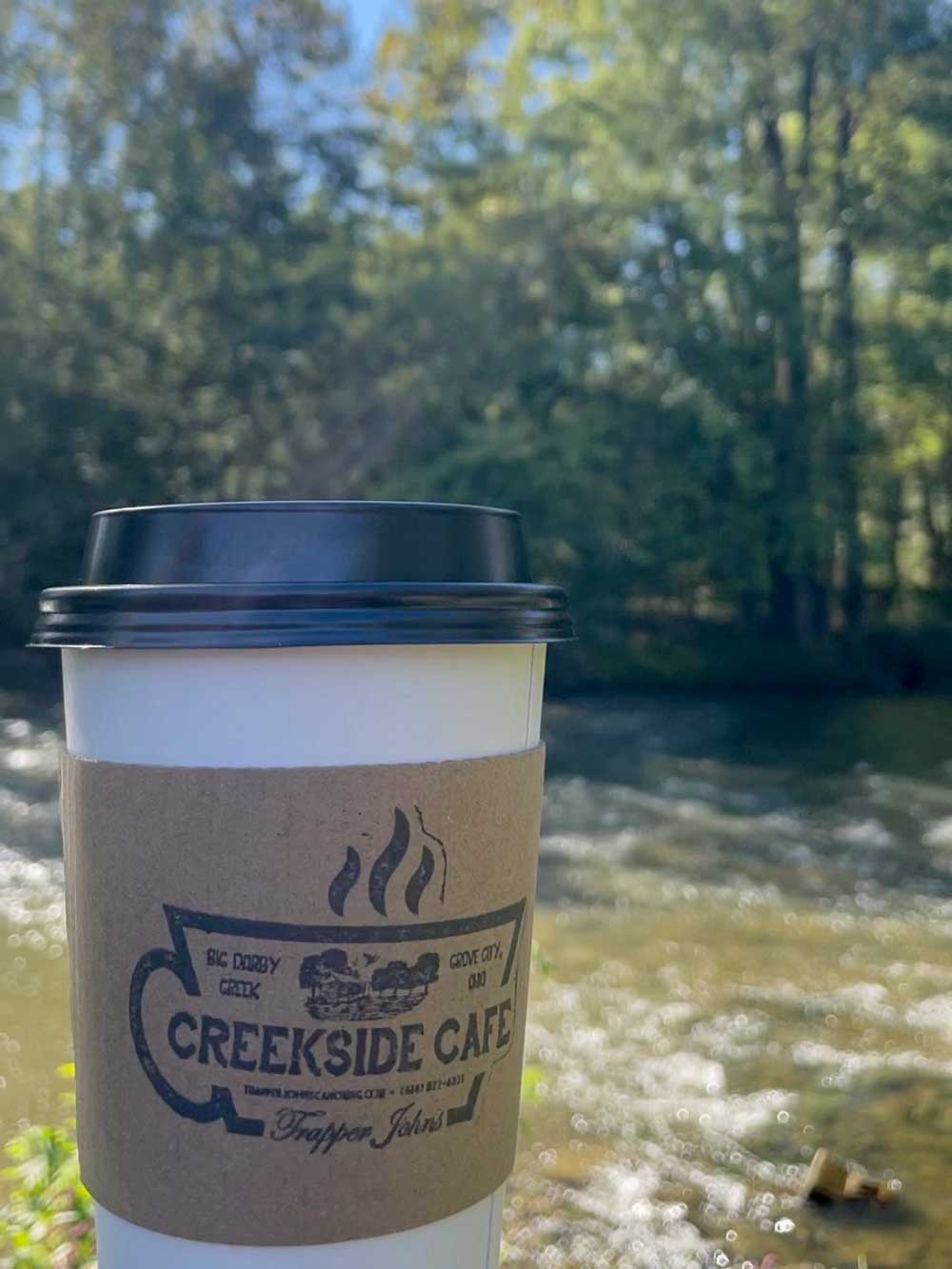 cup of coffee in front of creek