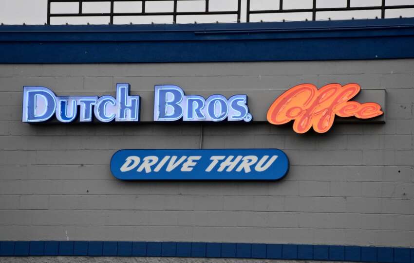 Dutch Bros Coffee neon sign and drive thru sign on a gray block wall