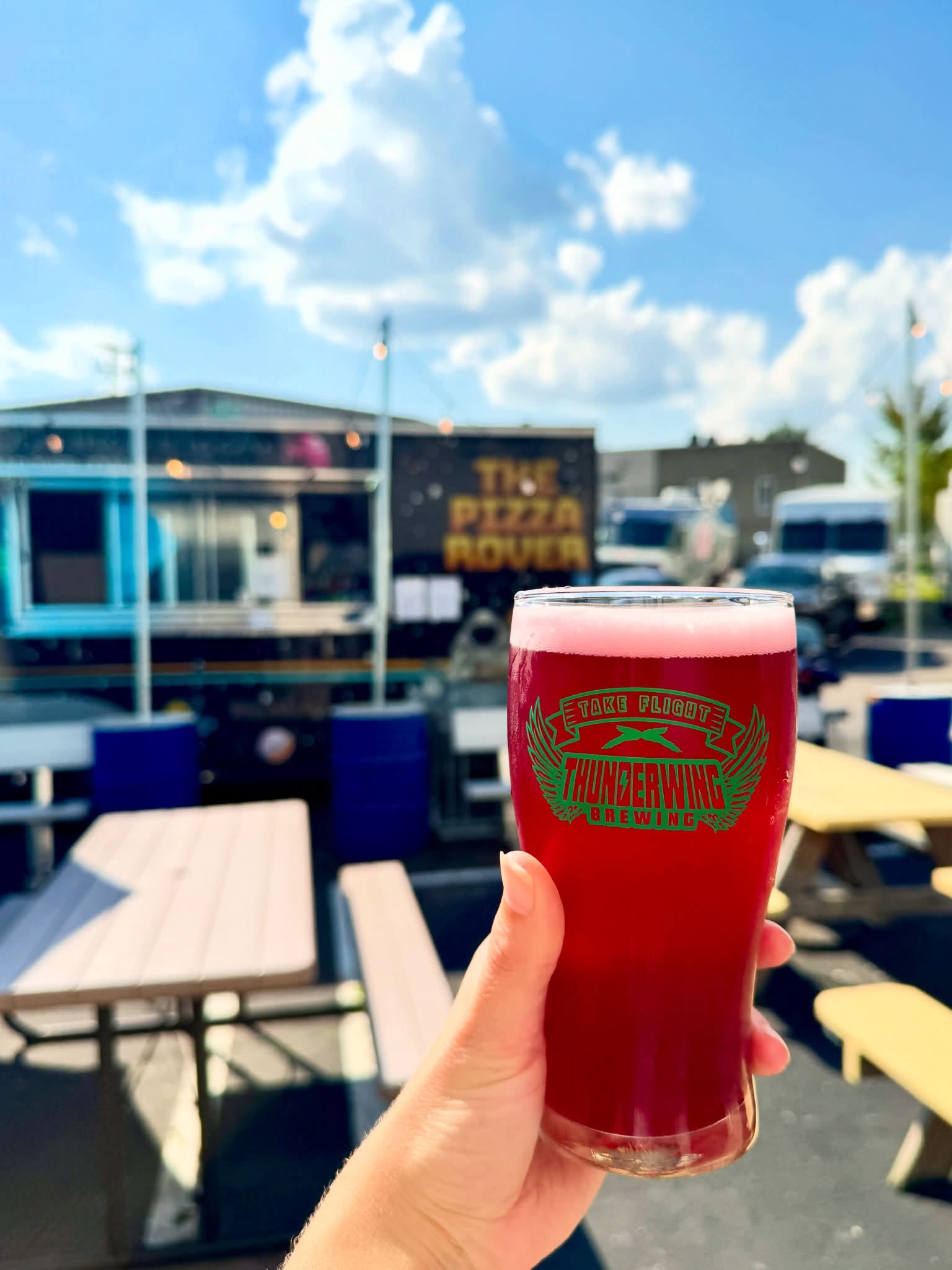 person holding beer in front of patio tables