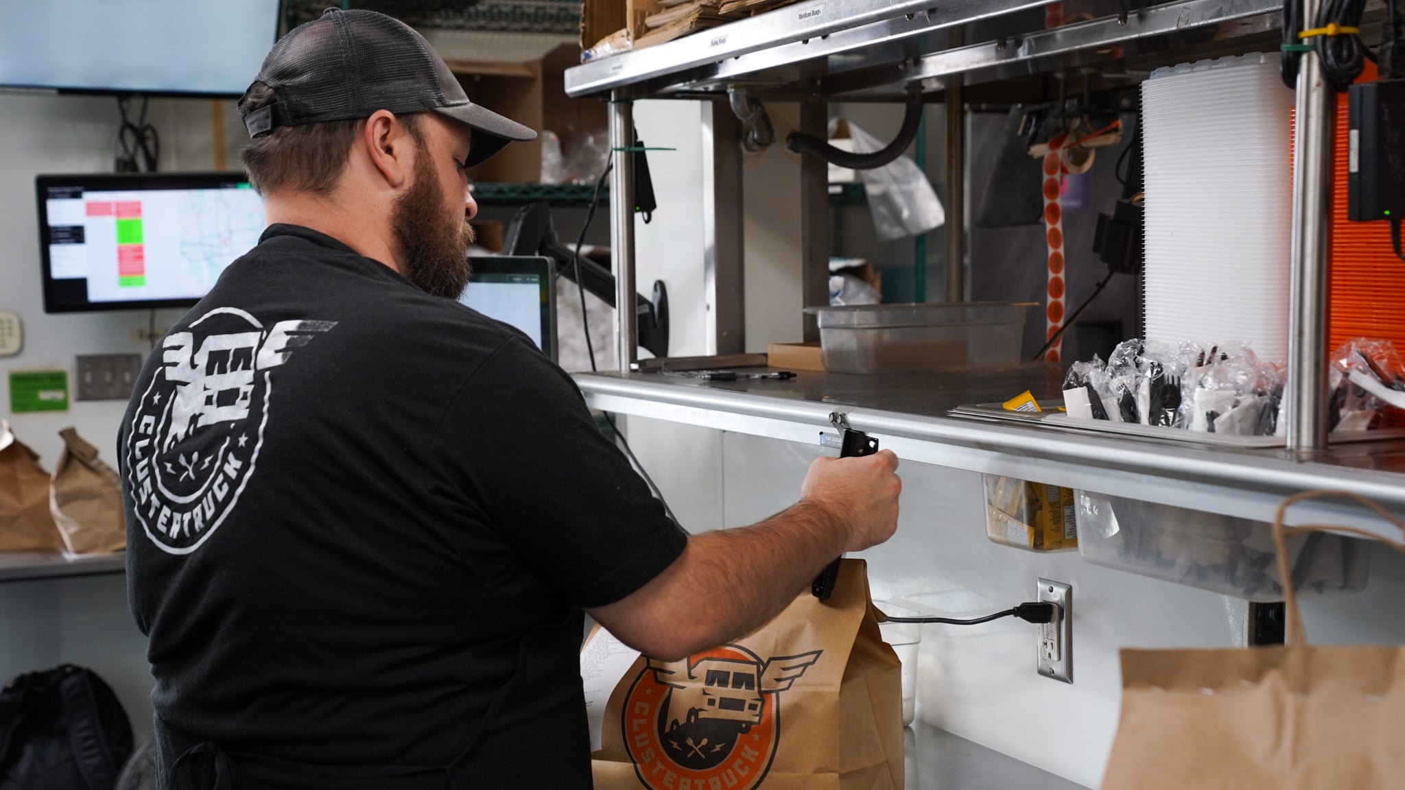 ClusterTruck Brings A Different Approach To Food Delivery In Columbus 4 man stapling to-go bag in kitchen