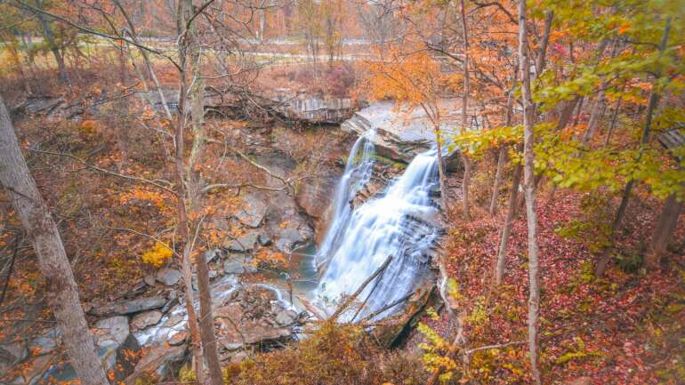 10 Fall Getaways In Ohio Worth The Drive From Columbus 8 Brandywine Falls pouring over the sandstone ledge at Cuyahoga Valley National Park, surrounded by orange and yellow fall foliage