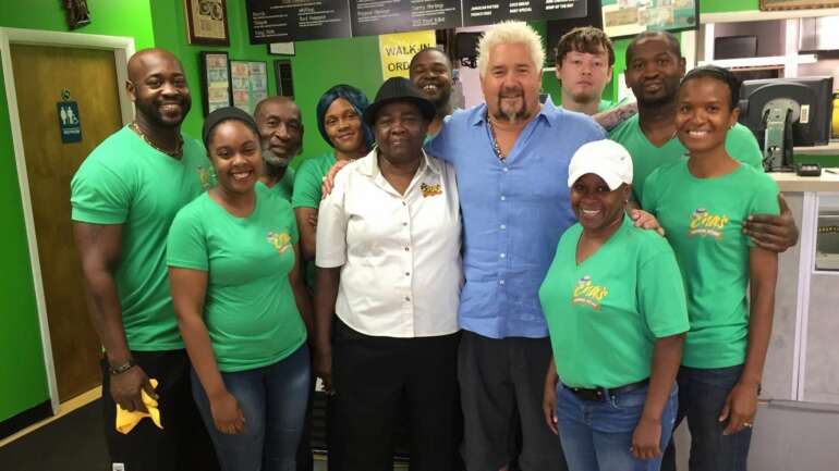 Guy Fieri poses with the staff of Ena's Caribbean Kitchen inside the restaurant