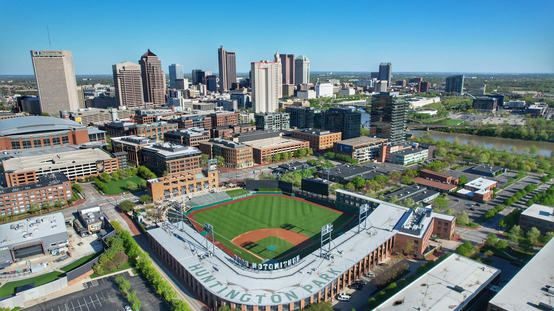 Banana Ball Is Coming Back To Columbus In 2027. Here's How The Ticket Lottery Works 1 Aerial view of Huntington Park with the downtown Columbus skyline and the Scioto River behind it
