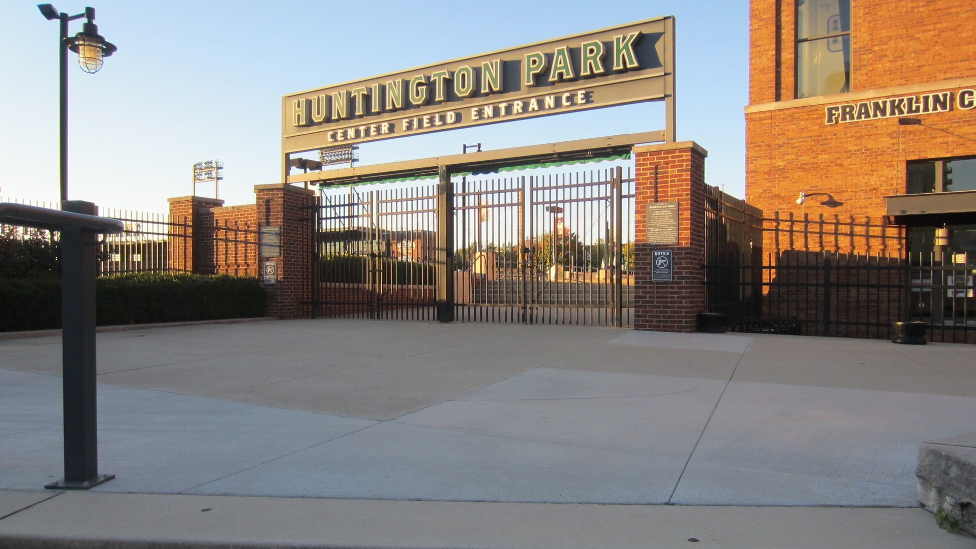 Banana Ball Is Coming Back To Columbus In 2027. Here's How The Ticket Lottery Works 2 The Huntington Park Center Field Entrance gate and sign in low evening sun, with a brick building at right