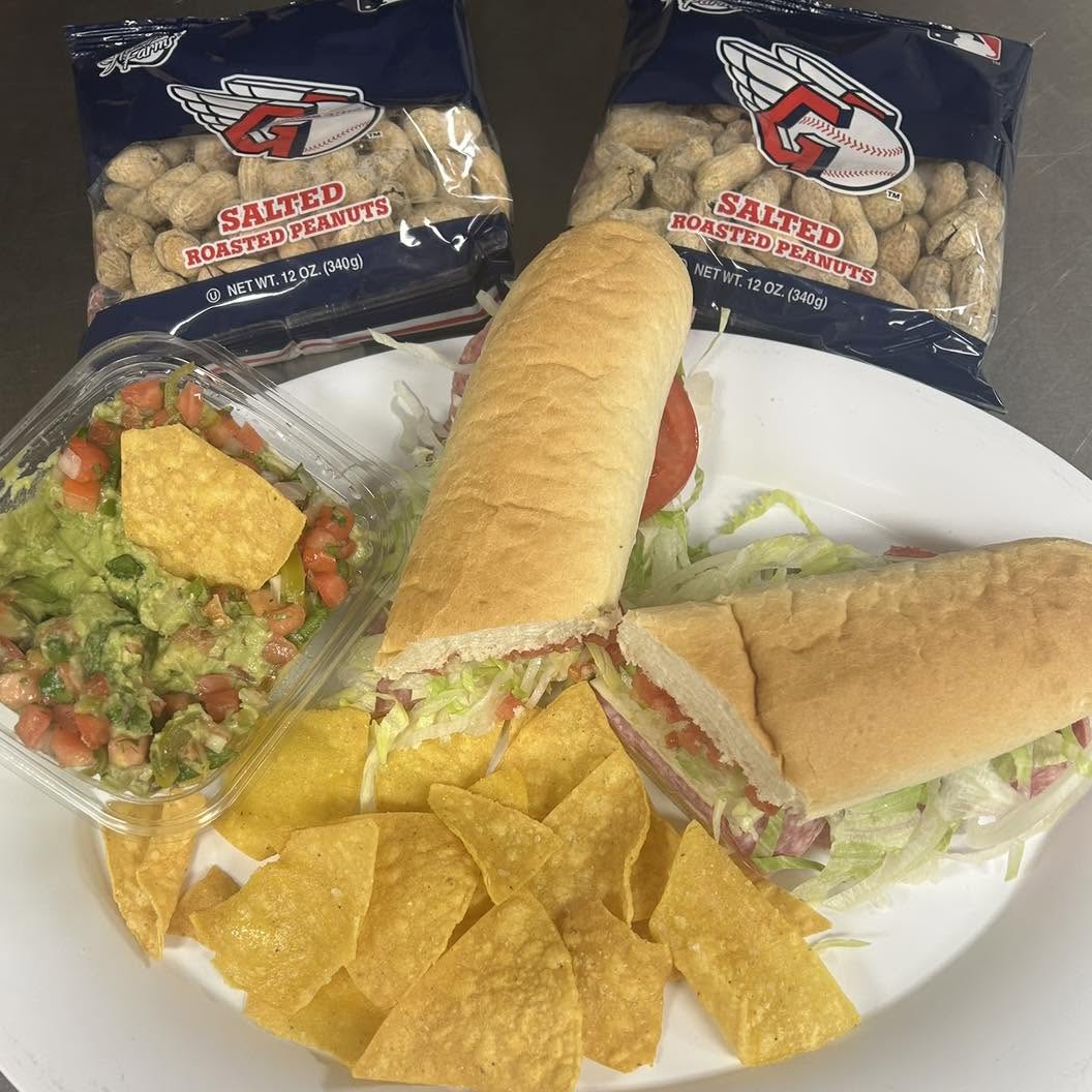 a plate with a sub sandwich, chips, and a salad