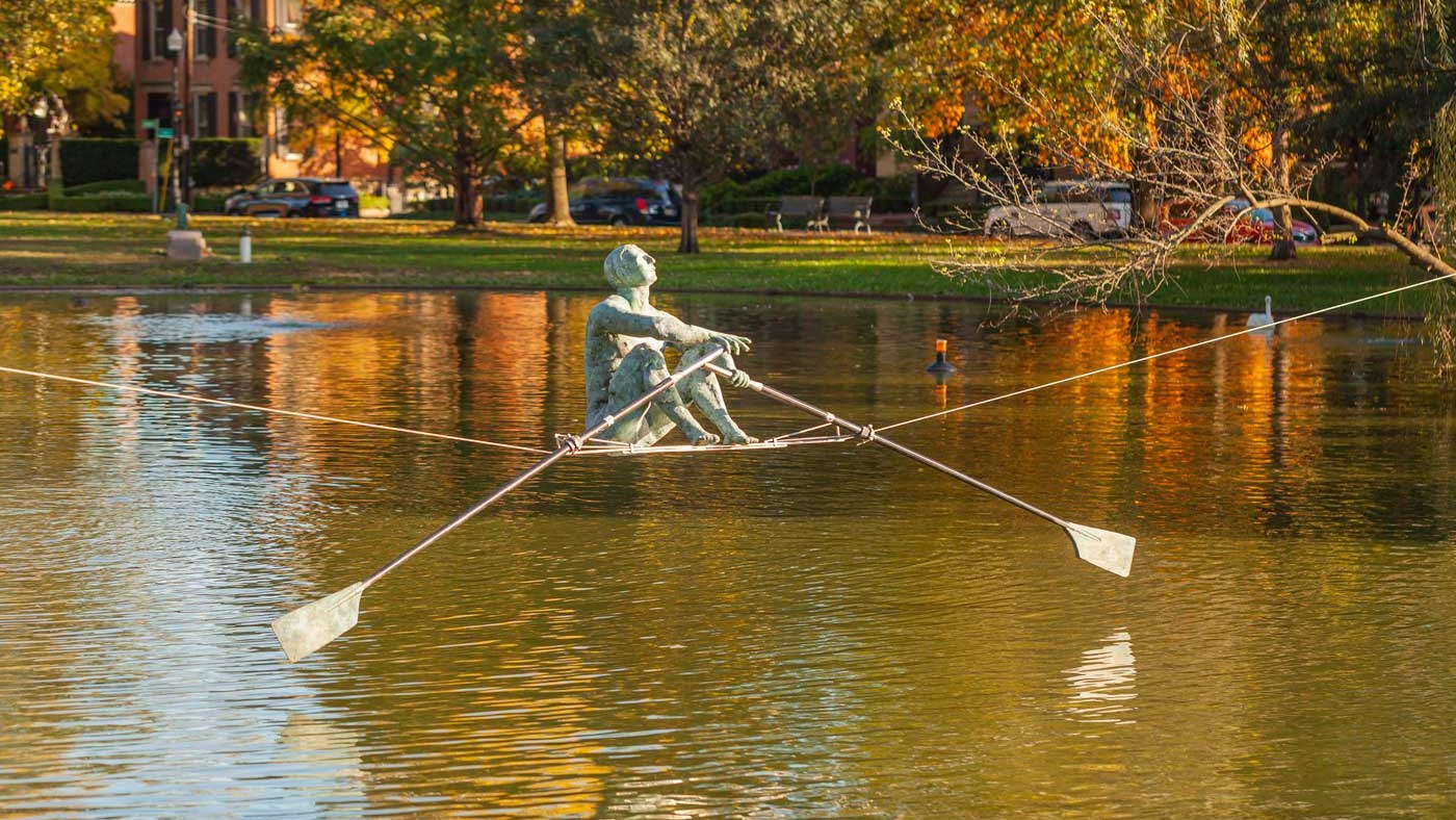 The Best Things To Do In Columbus This Weekend (October 9–11) 7 A bronze rower sculpture suspended over the pond at Schiller Park, with fall leaves behind